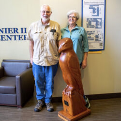 couple standing by statue of bird award