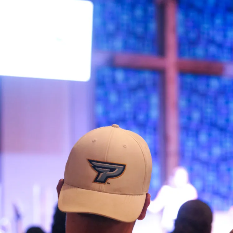 A Point logo on a hat with a cross in the background