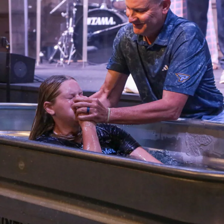 A young lady getting baptized by a a pastor